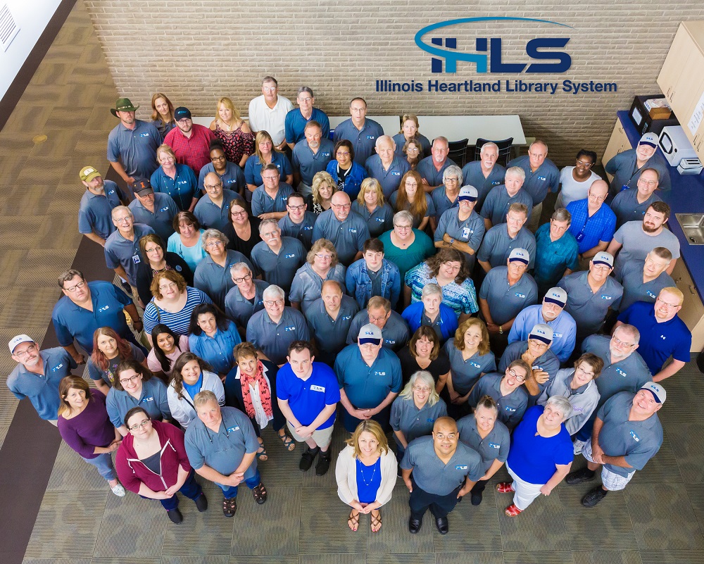 IHLS Staff overhead view -- Illinois Heartland Library System logo is seen in the background